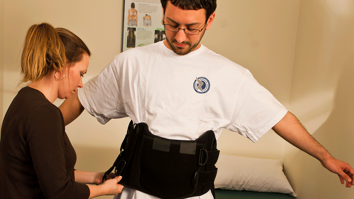 female practitioner fitting brace on male patient