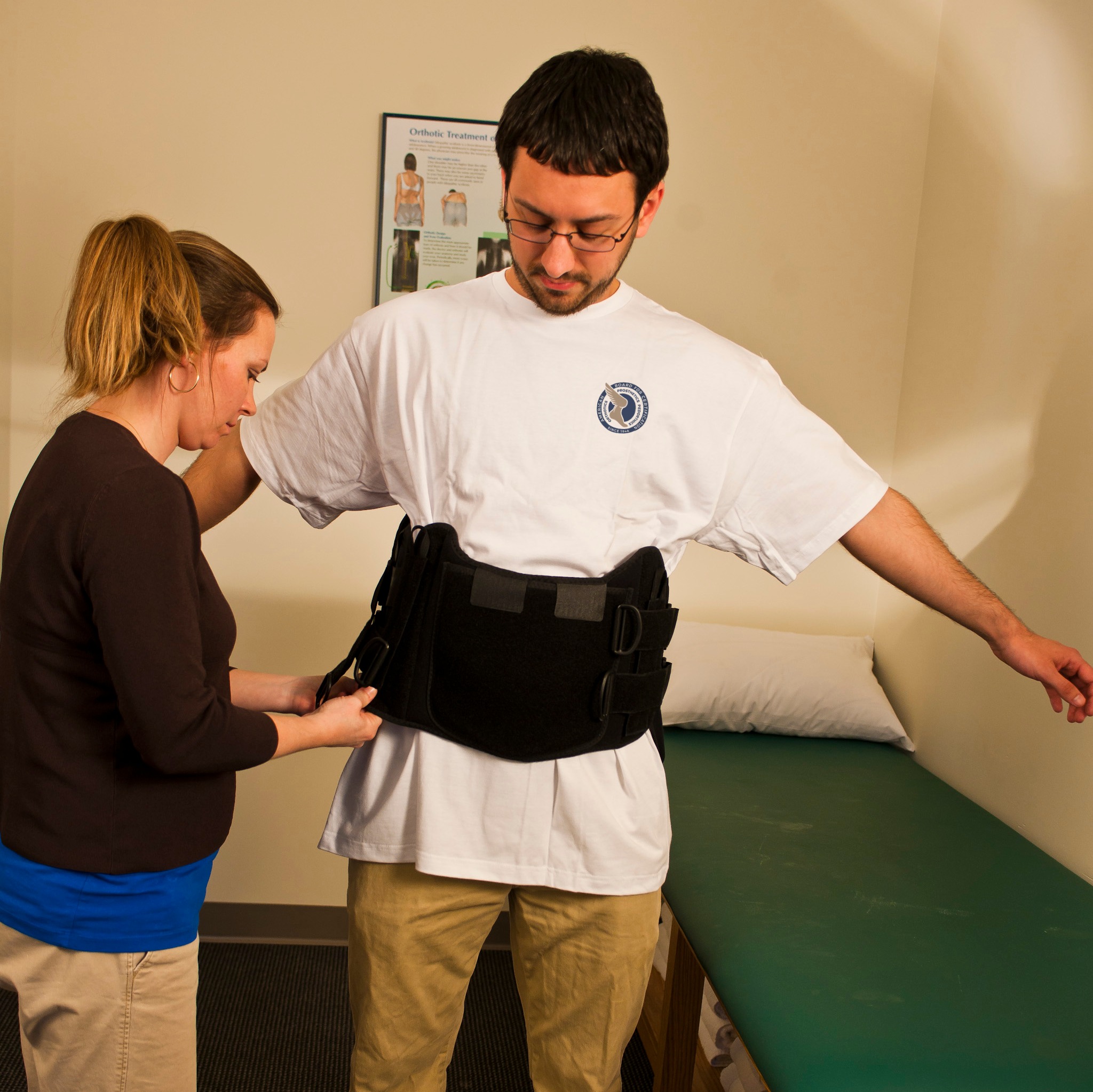 adult female practitioner fitting back brace on adult male patient